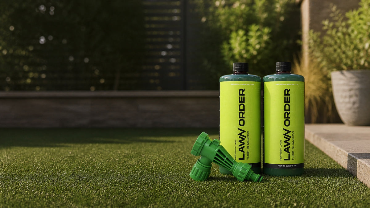 Two LawN Order Enzyme bottles and a green hose-end sprayer on an outdoor lawn